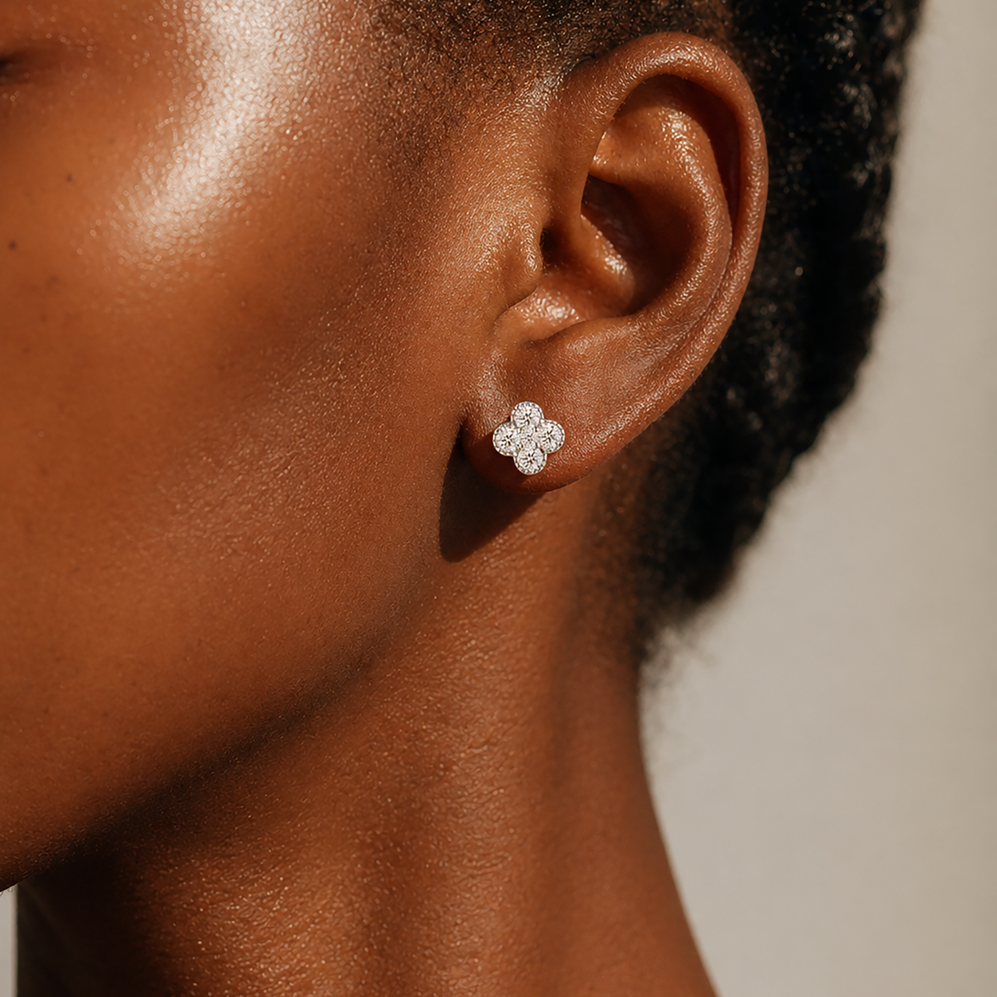 Close-up of silver flower moissanite earrings worn on deep skin tone