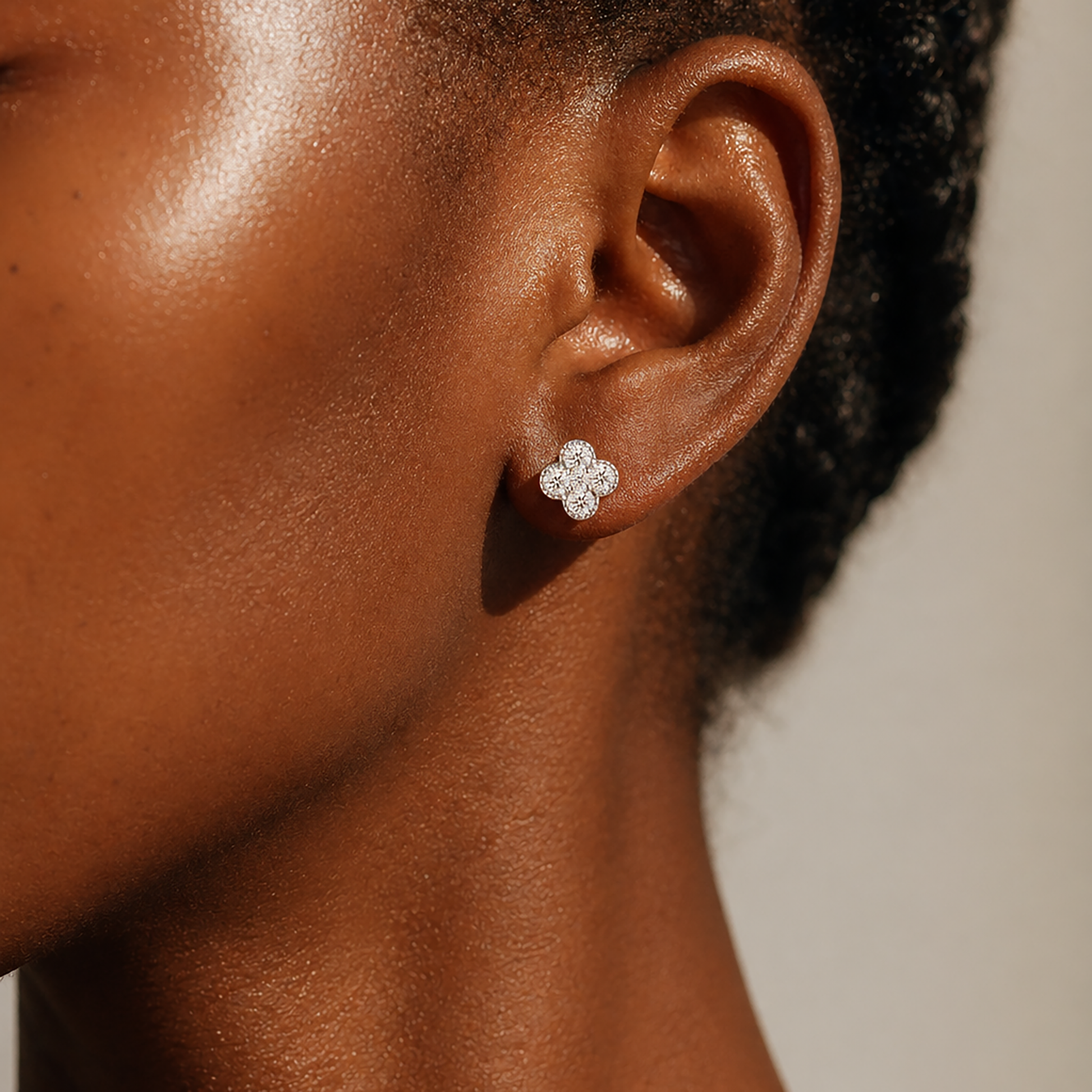 Close-up of silver flower moissanite earrings worn on deep skin tone