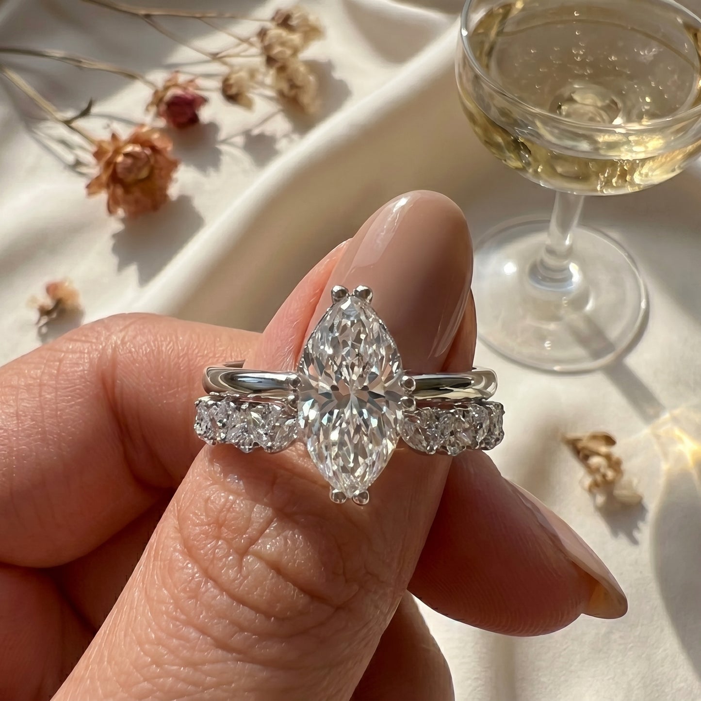 Close-up of a shimmering 3.0 CT marquise interlocking combination ring worn on hand in a premium aesthetic lifestyle setting with soft sunlight shadows.