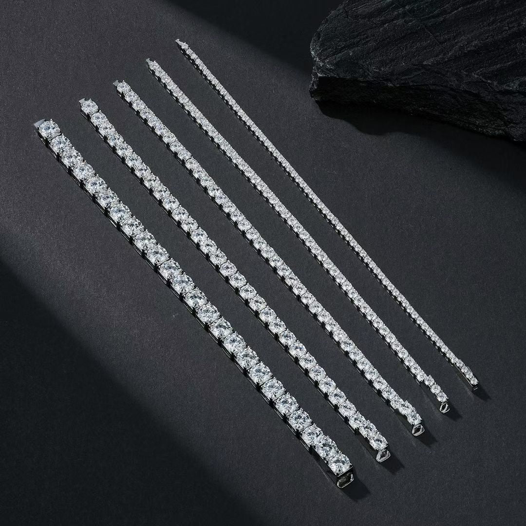 Multiple shimmering silver moissanite tennis bracelets laid out parallel on a luxury dark stone background.