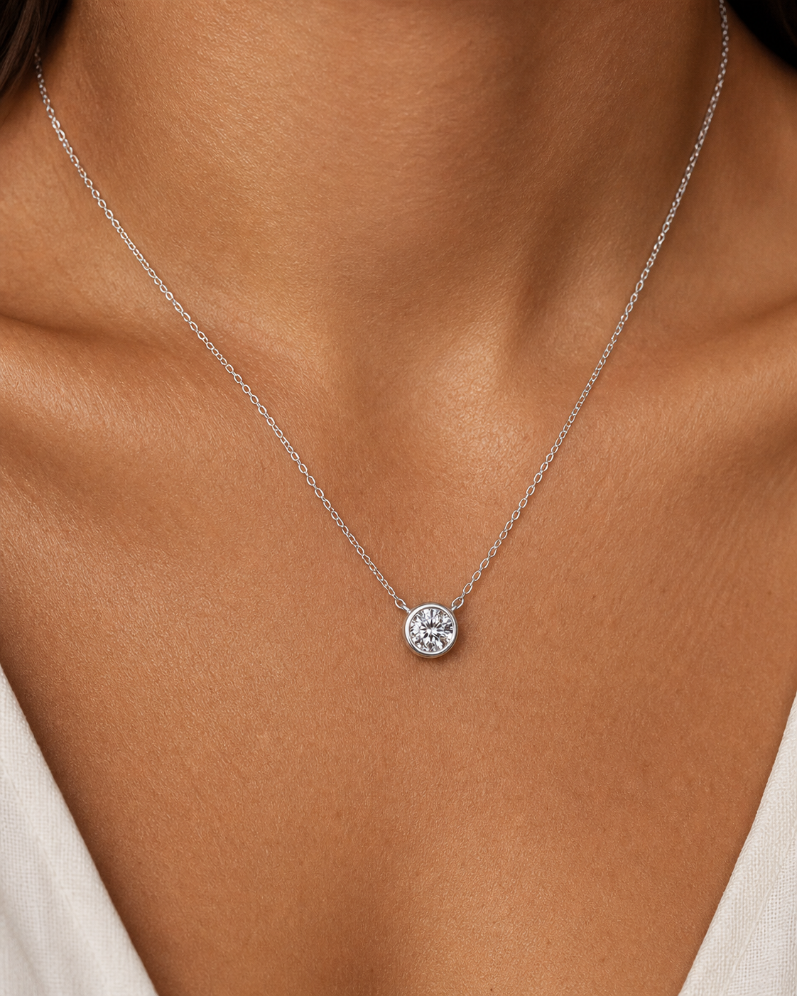 Silver round moissanite pendant necklace worn on tan skin