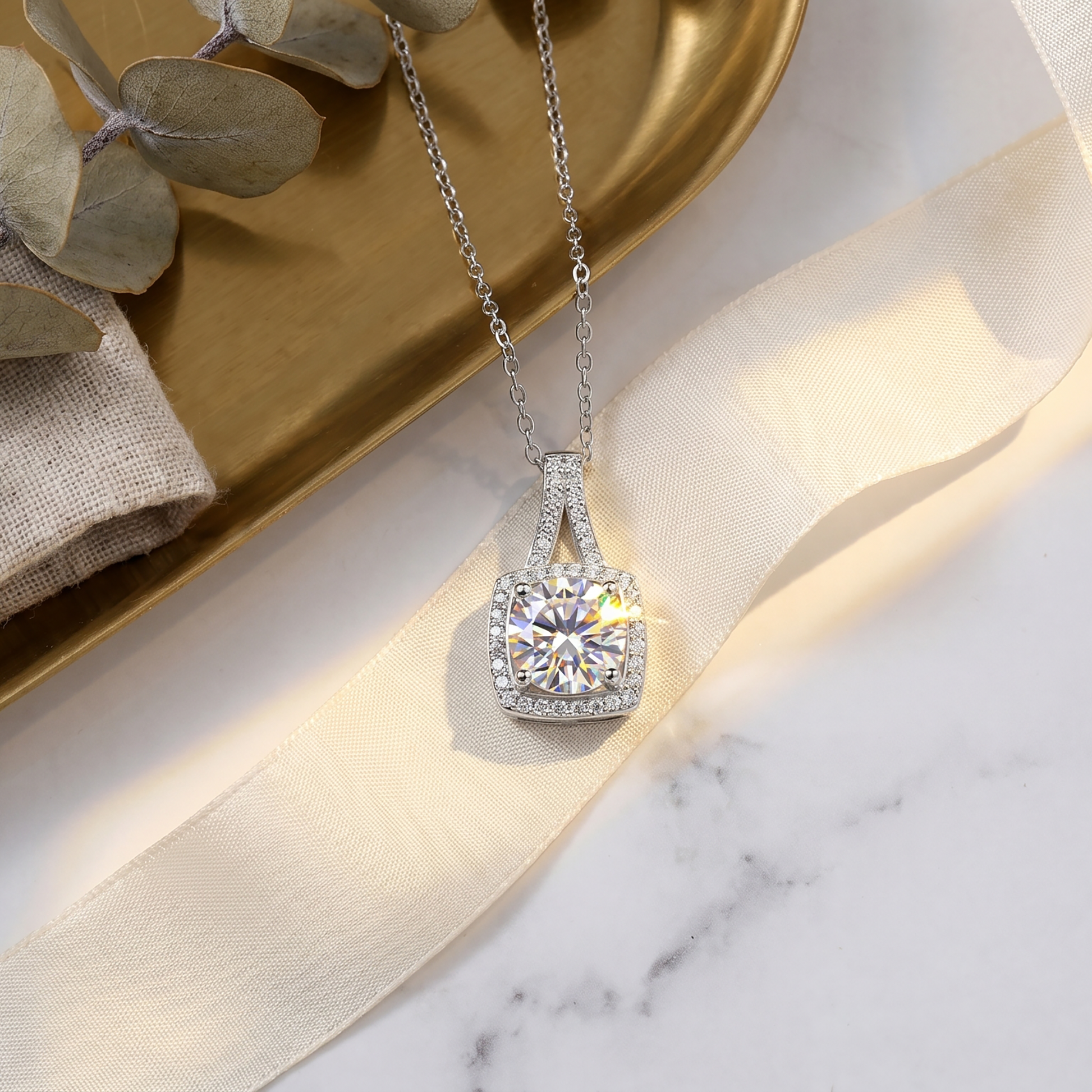 Cushion halo moissanite pendant necklace styled on white marble and gold tray
