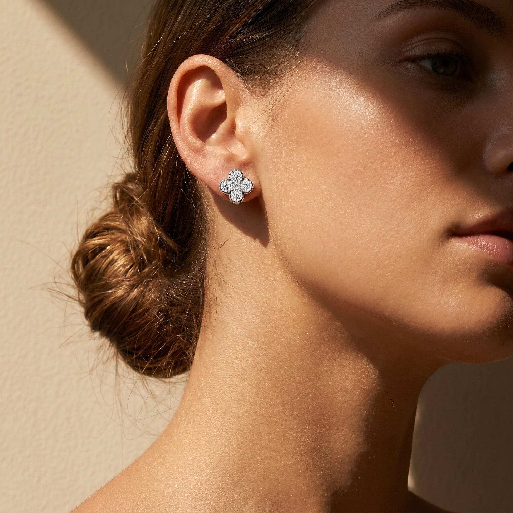 Woman wearing silver flower cluster moissanite stud earrings in soft natural sunlight