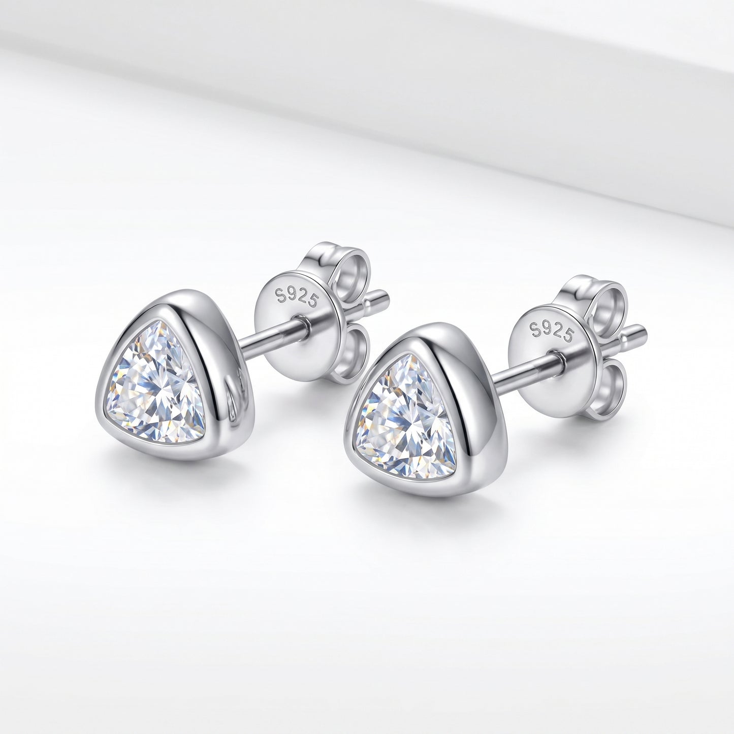 A pair of solid 925 sterling silver low-profile geometric bezel setting moissanite studs shown from a sharp side-angle view.
