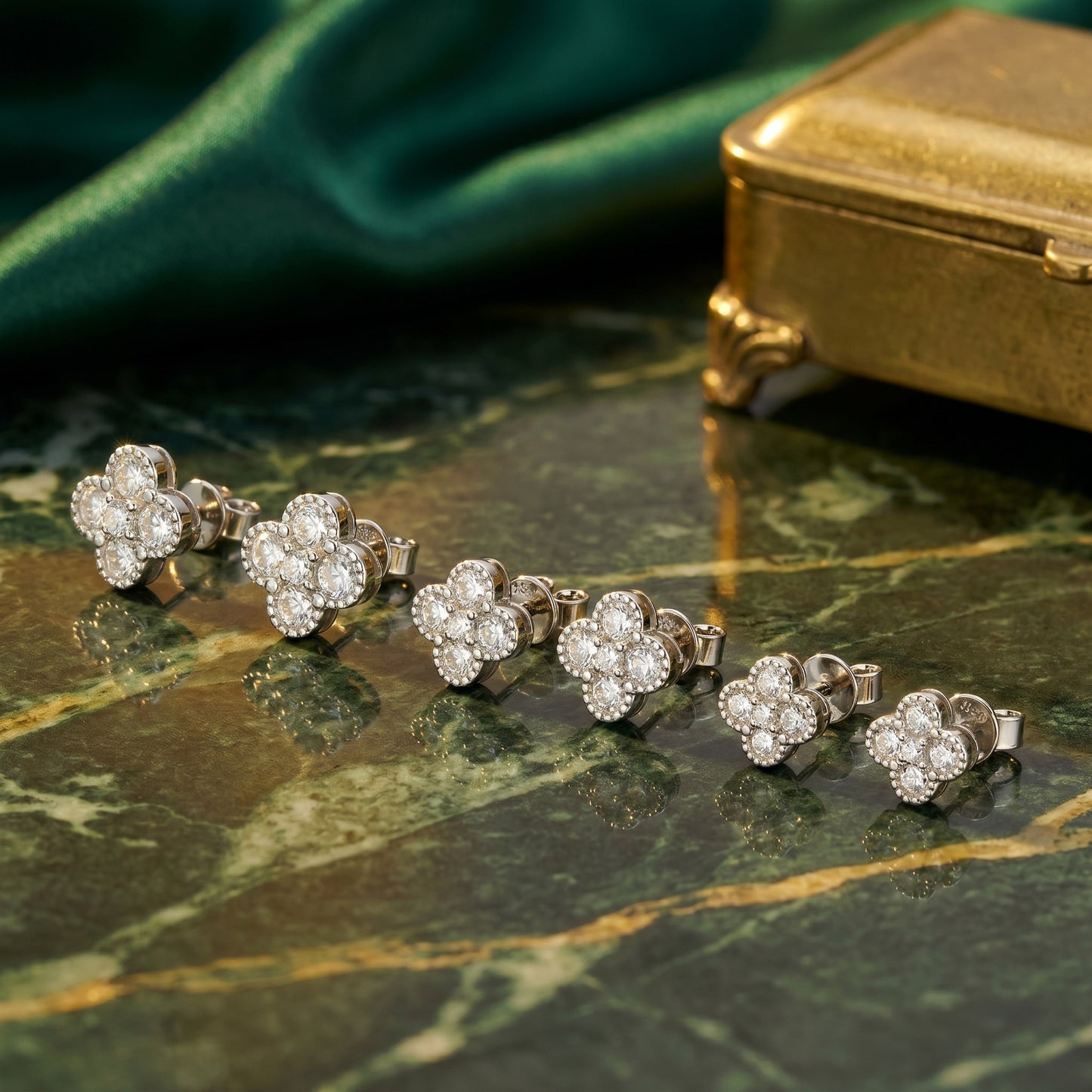 Silver moissanite flower stud earrings styled on green marble with gold box