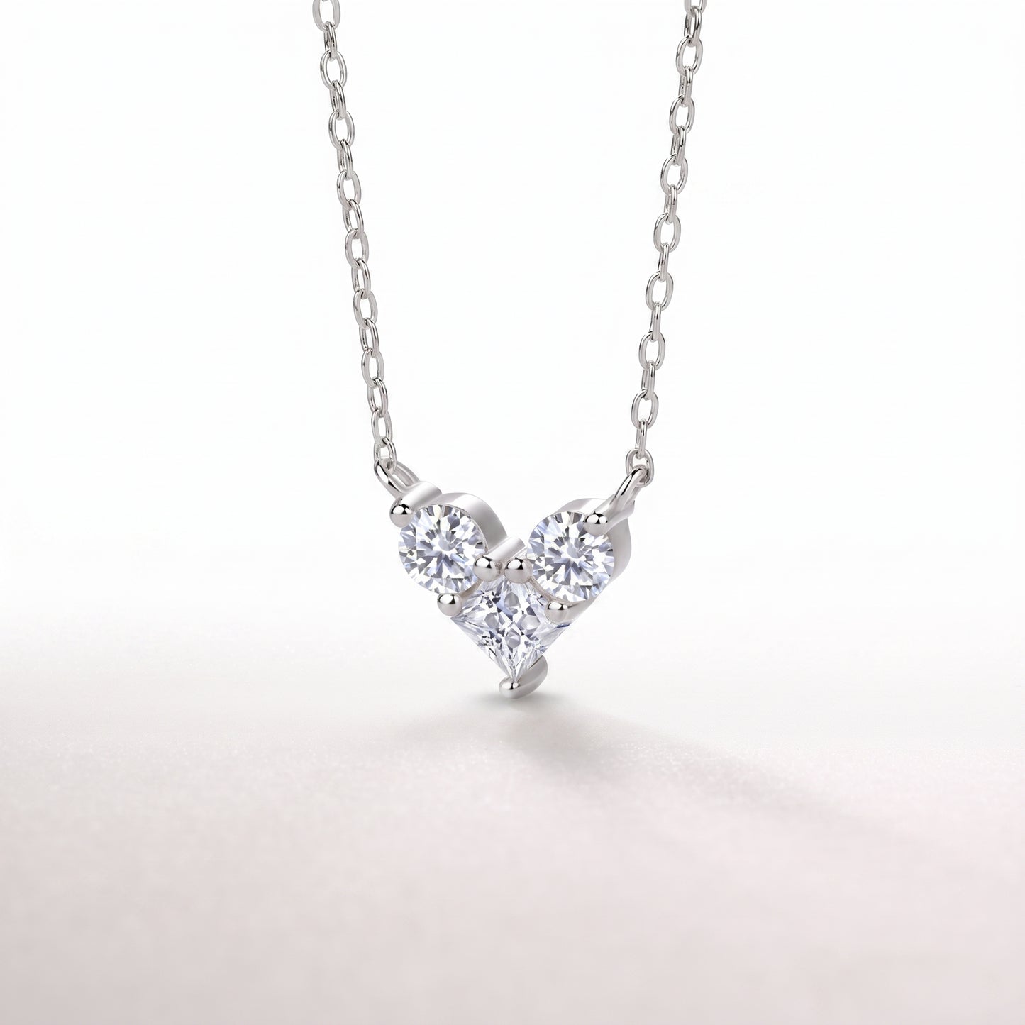 Side angle close-up of a high-brilliance interlocking heart-shaped moissanite pendant with an open-back setting.