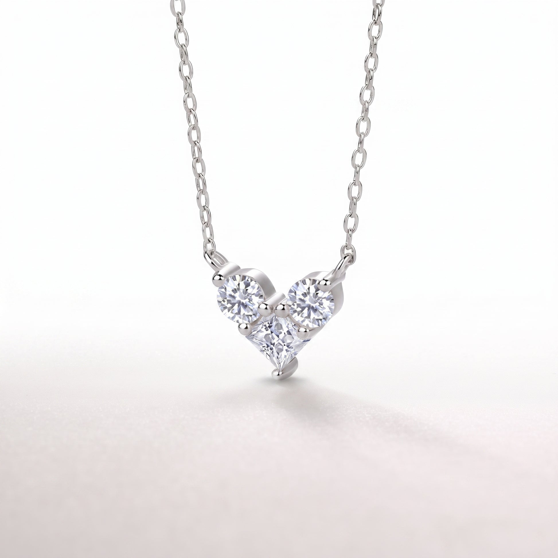Side angle close-up of a high-brilliance interlocking heart-shaped moissanite pendant with an open-back setting.