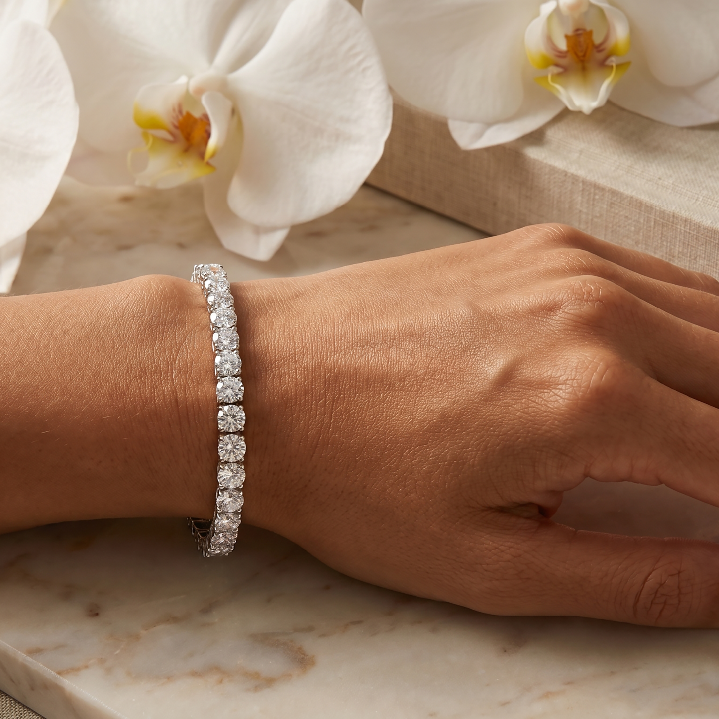 Woman wearing a silver moissanite tennis bracelet with white orchids