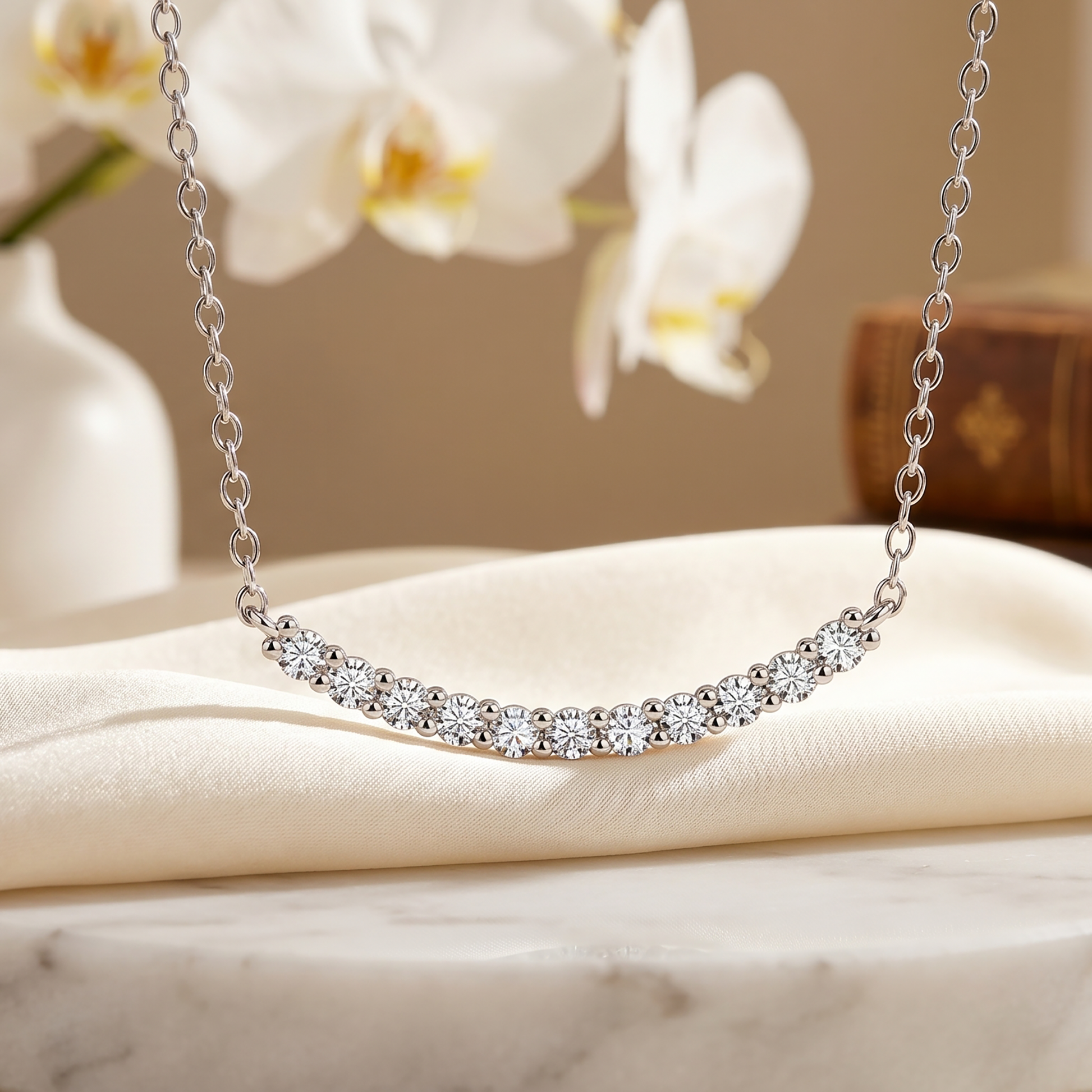 Curved moissanite bar necklace styled with white flowers on soft fabric
