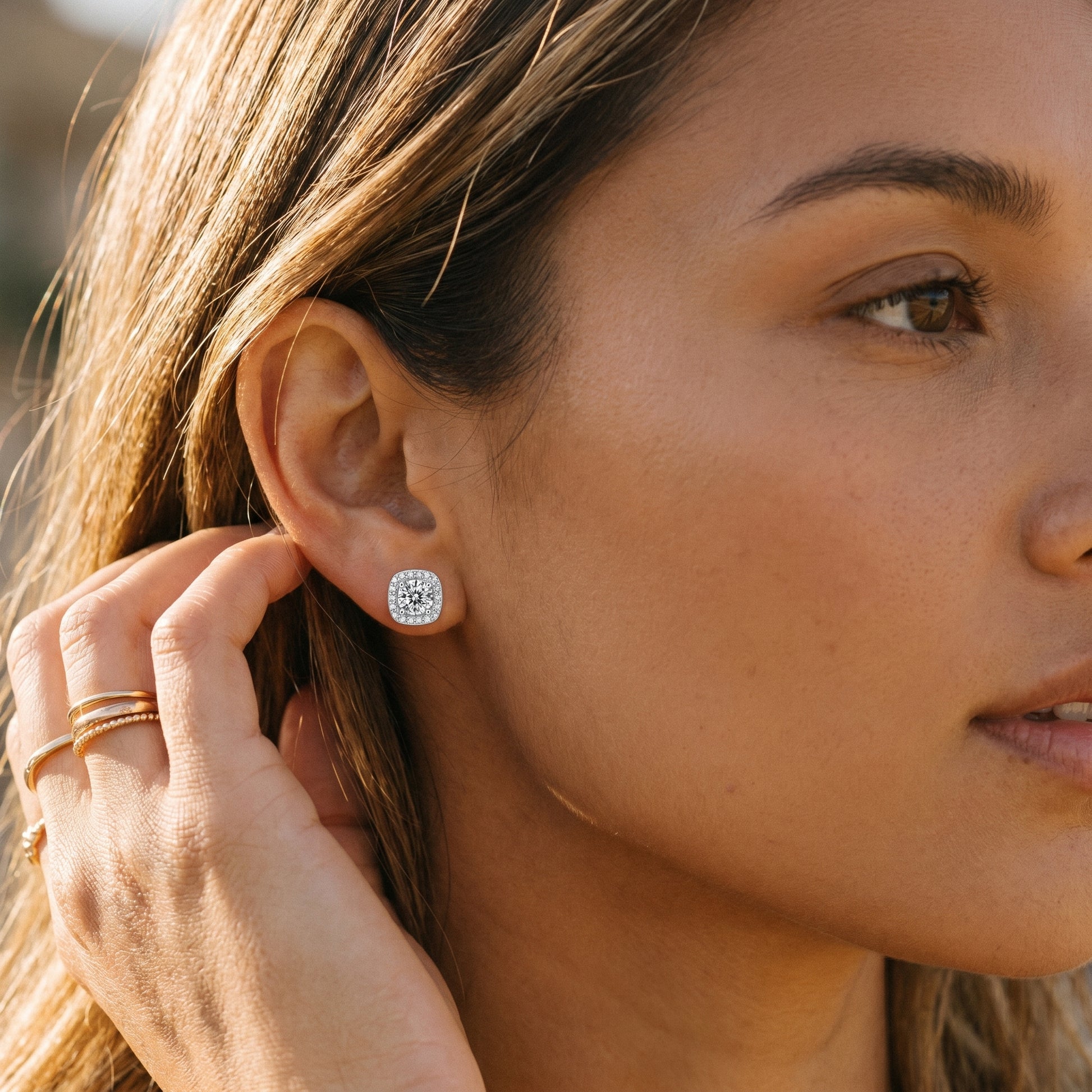 Close-up of cushion halo moissanite earrings worn on warm skin tone
