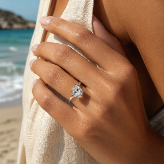 Close up of a woman with beautiful sun-kissed tan skin wearing a 4.5ct oval moissanite engagement ring at the beach