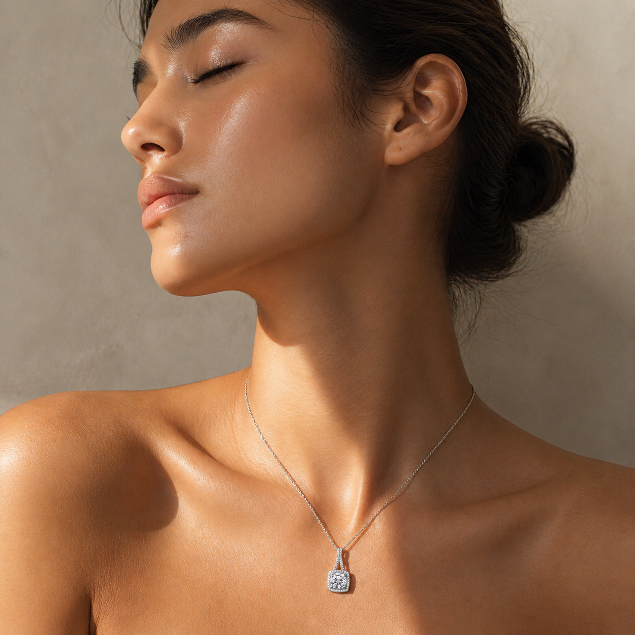 Woman wearing a cushion halo moissanite pendant necklace in soft natural sunlight