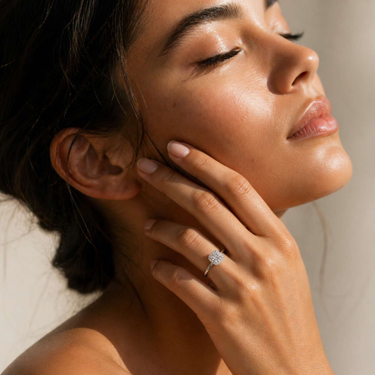 Woman wearing a cushion halo moissanite ring in soft natural sunlight