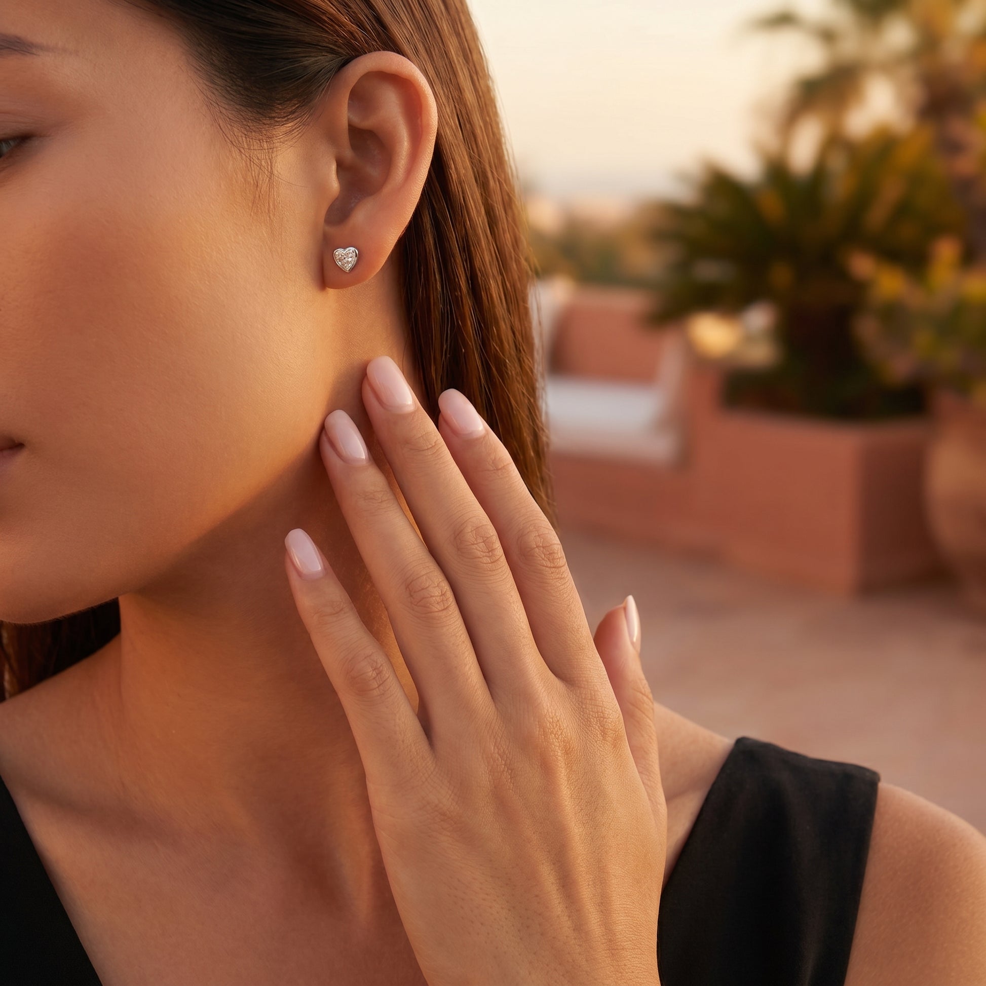Sleek on-ear lifestyle look of Luvia romantic heart moissanite stud earrings displayed on a tanned skin tone model.